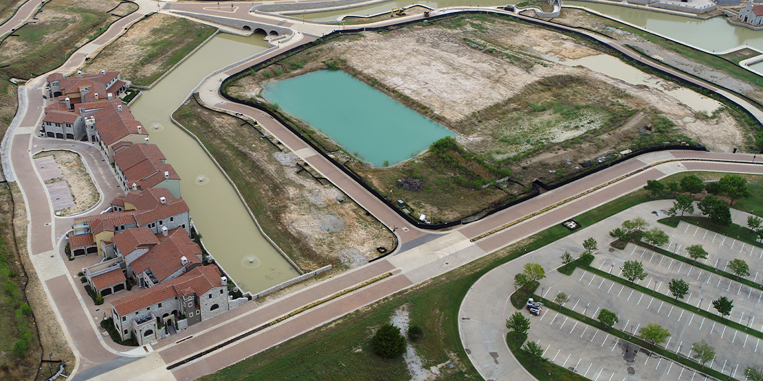 An aerial view of houses next to a retention pond at Westlake Entrada