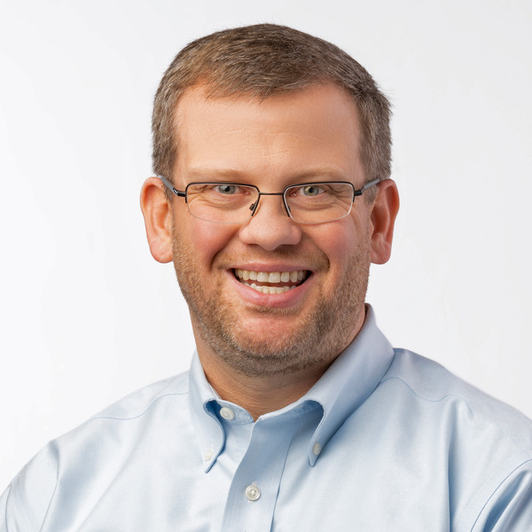 Professional headshot of Eric Hampton, smiling against a white background.