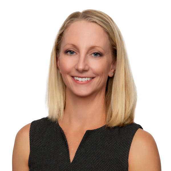 Professional headshot of Jenny Urcan, smiling against a white background.