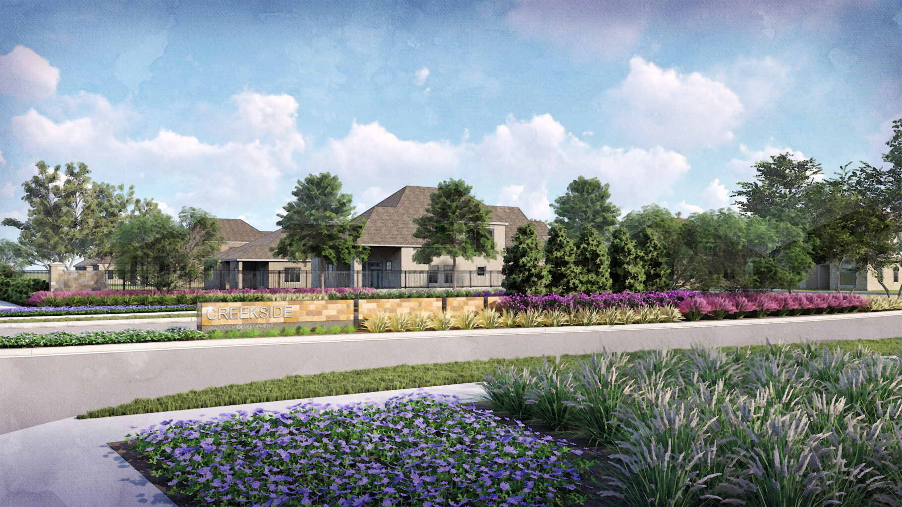A landscaped entrance with flowers, shrubs, and a sign reading Creekside stands in front of a large house with a gray roof, nestled along the ridgeline and surrounded by trees under a blue sky with clouds.