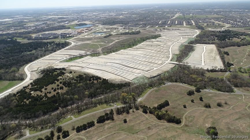 Aerial view of a large cleared area with grid-like plots, surrounded by green spaces, trees, and distant residential neighborhoods under a clear sky—a striking landscape captured by Steve Linhart.